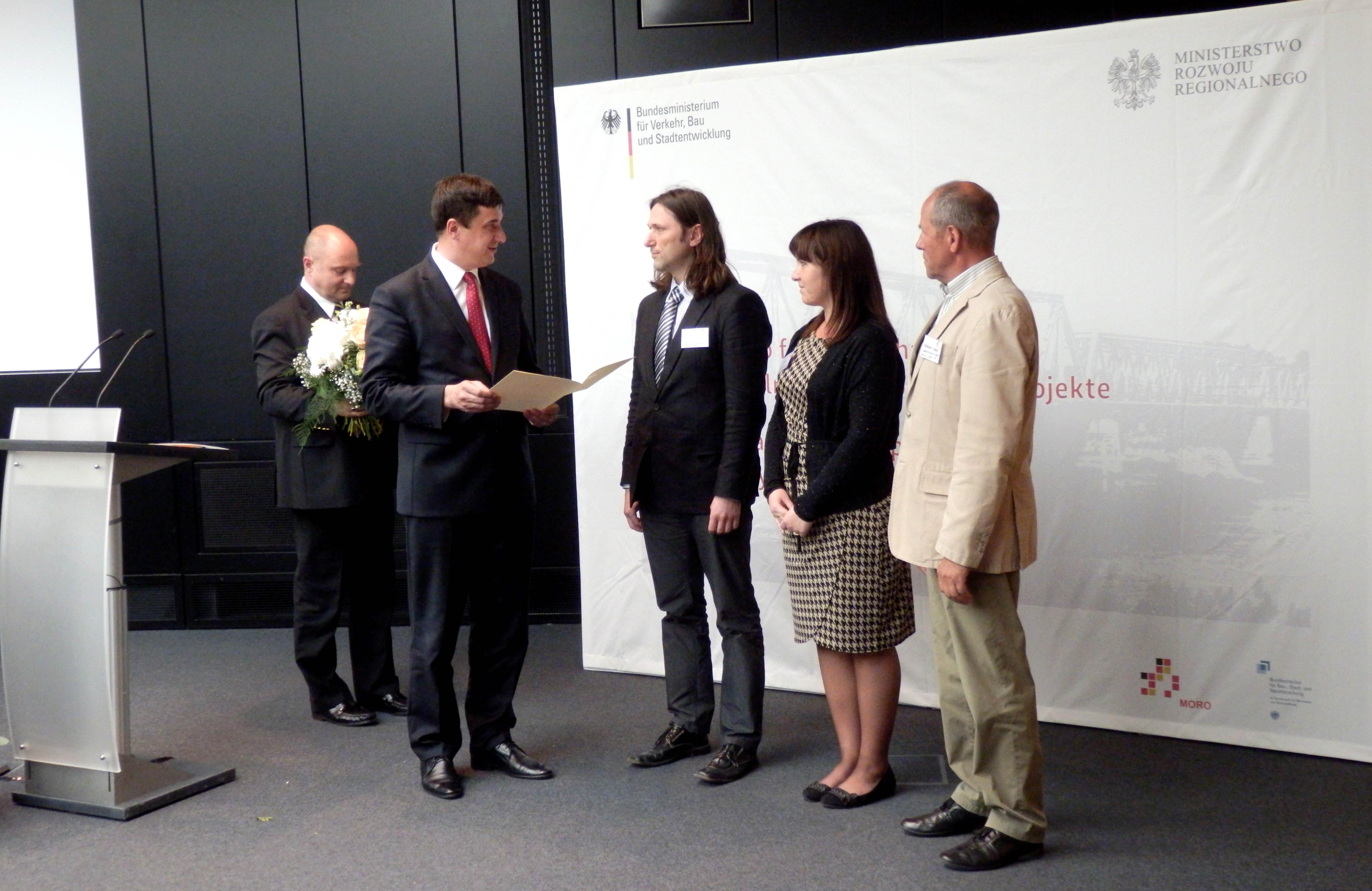 Wiceminister Marceli Niezgoda i sekretarz stanu Rainer Bomba wręczają dyplom Michałowi Urbańskiemu, kierownikowi projektu po stronie polskiej. Obok -Lilli Wolny i Jürgen Stahl, kierownik projektu po stronie niemieckiej.