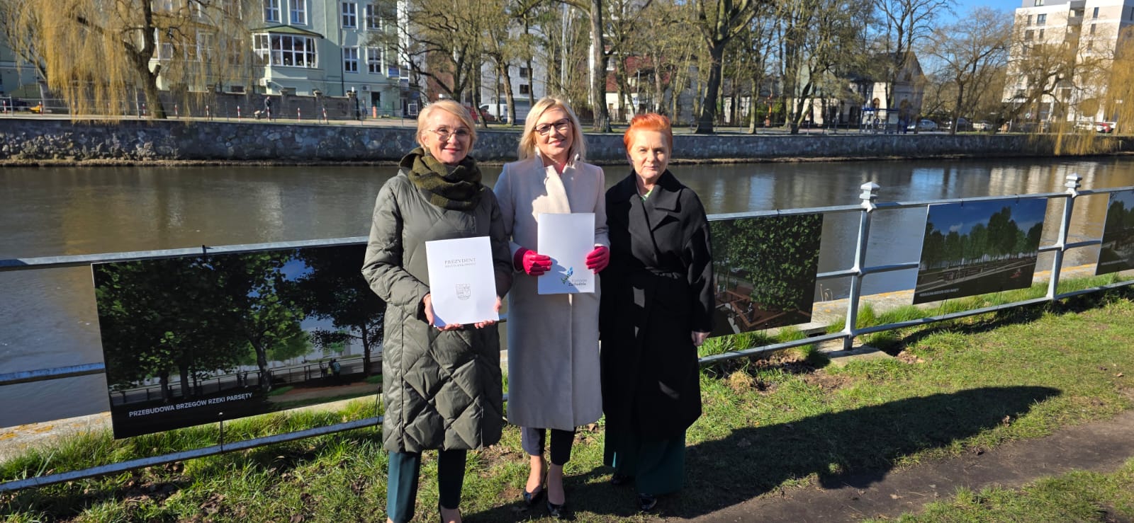 Strony porozumienia prezentują podpisany dokument, w tle brzegi i rzeka Parsęta - fot. Urząd Miejski w Kołobrzegu. 