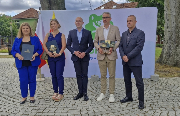 Dębno z nagrodą na najlepszą przestrzeń publiczną. Wicemarszałek Kowalik i władze Dębna prezentują otrzymaną statuetkę, w tle ścianka promocyjna gminy Dębno.