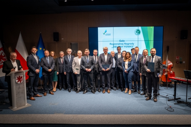 Laureaci nagrody Zielonego Feniksa na wspólnym zdjęciu, w tle scena i ekran z logo konkursu.