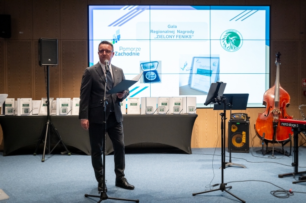 Członek Zarządu Bogdan Jaroszewicz wita ze sceny uczestników gali, w tle ekran z logo i nazwą konkursu. 