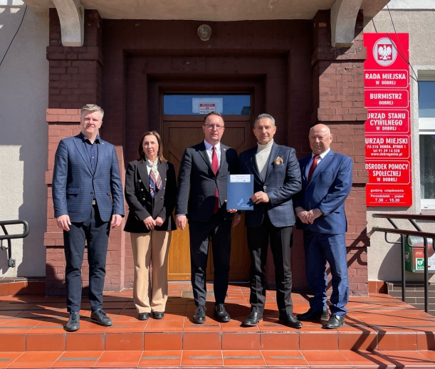 wspołne zdjęcie przed budynkiem gminy dobra burmistrza i gości obecych podczas podpisania umowy