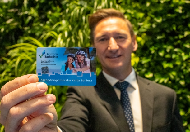 marszałek trzyma Zachodniopomorską Kartę Rodziny na tle zielonej ścianki