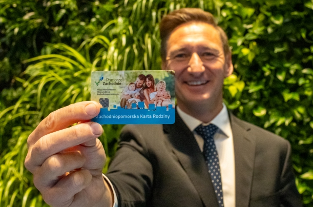 marszałek trzymZachodniopomorską Kartę Seniora na tle zielonej ścianki