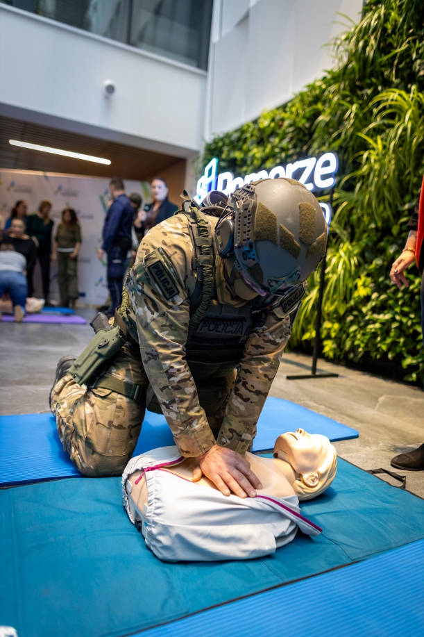 policjant w pełnym umundurowaniu ćwiczy nauke udzielania pierwszej pomocy
