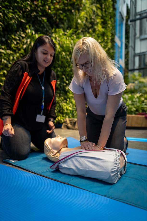 wicemarszałkini Anna Bańkowska ćwiczy naukę udzielania pierwszej pomocy, obok klęczy ratowniczka medyczna