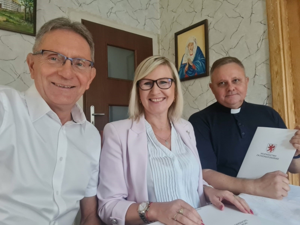 proboszcz parafii oraz wicemarszałkini po podpisaniu umowy przy stole 