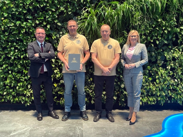 Dotacja dla POSP „Tryton” w Kołobrzegu. Sygnatariusze umowy prezentują podpisane porozumienie na zielonej ściance Urzędu Marszałkowskiego.