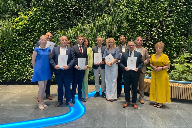 Kolejne samorządy z umowami na remonty zabytków i obiektów sportowych. Sygnatariusze umowy prezentują na wspólnej fotografii podpisane porozumienia, w tle zielona ścianka w urzędzie marszałkowskim.