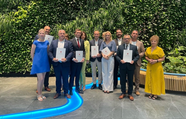 Kolejne samorządy z umowami na remonty zabytków i obiektów sportowych. Sygnatariusze umowy prezentują na wspólnej fotografii podpisane porozumienia, w tle zielona ścianka w urzędzie marszałkowskim.