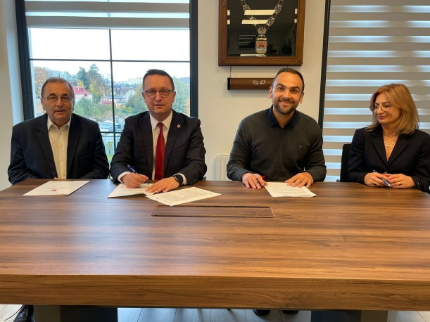 Syganatriusze umowy podpisuja porozumienie przy stole prezydialnym, w tle gabinet burmistrza Międzyzdrojów, okno. 