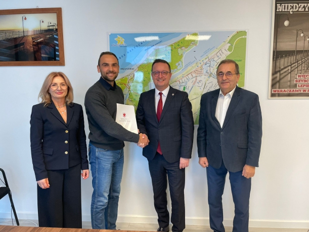 Sygnatariusze porozumienia prezentują podpisaną umowę, w tle mapa Międzyzdrojów. 