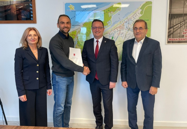 Sygnatariusze porozumienia prezentują podpisaną umowę, w tle mapa Międzyzdrojów.