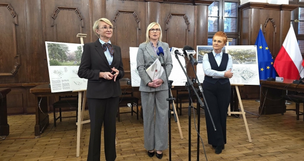 Strony porozumienia prezentują podpisany dokument, w tle wystrój ratusza i wizualizacje miejsca po zmianach. 