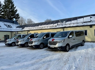 cztery srebrne auta stoja przed budynkiem zaz, na masce mają przyklejone ozdobne kokardy 