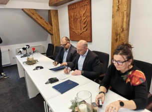 Strony umowy podpisują porozumienie przy stole prezydialnym.