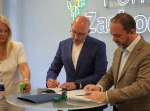 Sygnatariusze podpisują umowę o dofinansowanie, w tle ścianka promocyjna Pomorze Zachodnie.