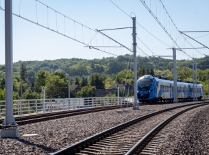 niebiesko-biały pociąg jedzie po torach w Podjuchach