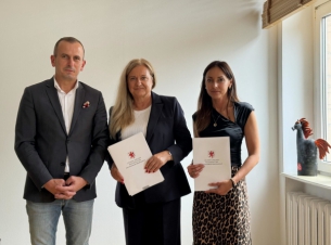Marcin Łapeciński stoi z dwiema benficjentkami, panie trzymają umowy w białych teczkach 
