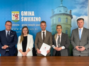 członek Zarządu Województwa stoi z beneficjentami przy ściance Gminy Świerzno