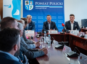 spotkanie marszałka w Starostwie Powiatowym w Policach, samorządowcy siedzą w sali sesyjej, w tle niebieskie banery