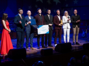 wspólne zdjęcie nagrodzonych na scenie, zwycięzca trzyma czek 