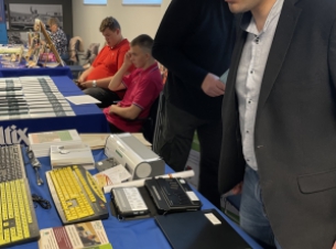 wystawca prezentuje sprzęt ułatwiający obsługę komutera przez osoby słabowidzące lub niewidzące, na stole np. klawiatury z kontrastowymi literami