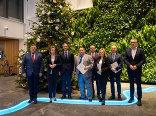 Marszałkowie i samorządowcy pozują do wspólnego zdjęcia prezentując podpisane umowy, w tle choinka.