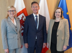 Władze samorządu województwa i ambsadorka Kanady pozują do wspólnego zdjecia, w tle flagi.