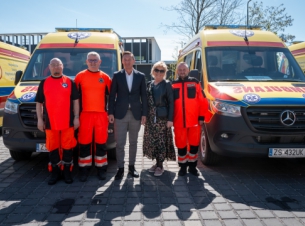 Marszałek Geblewicz i ratownicy medyczni stoją przed nowymi karetkami.