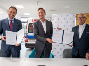 Marszałek Geblewicz i sygnatariusze umowy prezentują podpisany dokument, w tle banery i karetka szkoleniowa. 