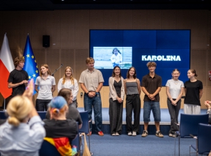 9 przedstawicieli młodzieży prowadzących konferencję stoi przed publicznością