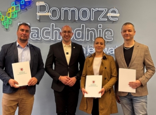 Wicemarszałek Kowalik i beneficjent prezentują podpisaną umowę, w tle ścianka promocyjna Pomorza Zachodniego.