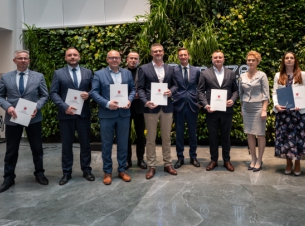 Marszałek Geblewicz i beneficjenci podczas wspólnego żdjęcia na zielonej ściance w Urzędzie Marszałkowskim. 