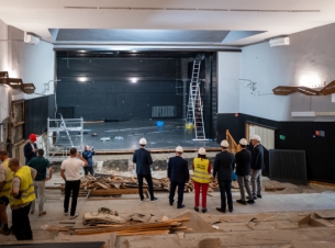 Prace rozbiórkowe w budynku Nowogardzkiego Domu Kultury, pracom przygląda sę grupa urzędników, na głowach mają białe kaski, patrzą w kierunku sceny  