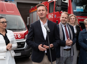 Marszałek Województwa Zachodniopomorskiego Olgierd Geblewicz na tle wozów strażackich stoi przed mikrofonem