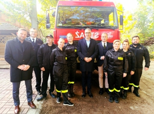 zdjęcie grupy ludzi - druhów OSP i polityków - na tle wozu strazackiego  