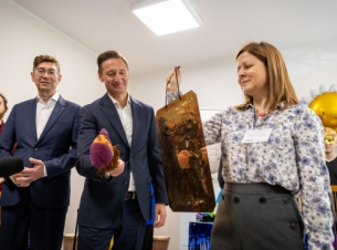 Marszałek Geblewicz uderza w gong na znak otwarcia oddziału, w tle inne osoby, ściany, instrumenty.