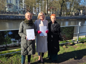 Strony porozumienia prezentują podpisany dokument, w tle brzegi i rzeka Parsęta - fot. Urząd Miejski w Kołobrzegu. 