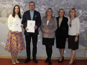 Strony umowy prezentują podpisane dokumenty, w tle ścianka z widokiem na gminę Kobylanka - fot. Urząd Gminy Kobylanka.