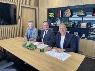 trzech samorządowców siedzi za stołem w gabinecie i podpisują umowy 