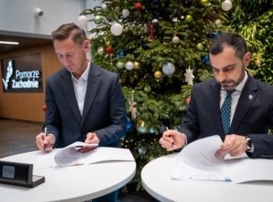 Strony umowy podpisuja porozumienie, w tle choinka. 