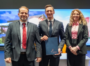 Sygnatariusze prezentują podpisaną umowę, w tle scena sali kinowej i wizualizacje nowego budynku.