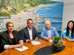 Uczestnicy podpisania parafują dokumenty przy stole prezydialnym. 