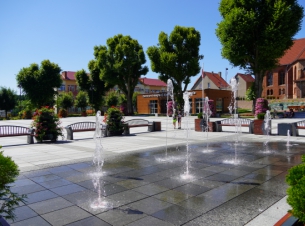 Rynek w Polanowie po rewitalizacji, zdjęcie zrobione latem, na pierwyszm planie fontanna 