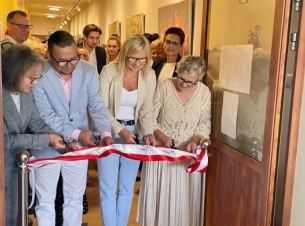 Uczestnicy otwarcia Centrum przecinają wstęgę, w tle obiekt i inne osoby.