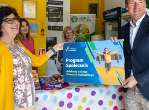 Marszałek Geblewicz w siedzibie Jadłodzielni, trzyma banner z napisem Program Społecznik 