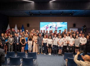 Goście gali podczas wspólnego zdjęcia, w tle ekran ze slajdem poświęconym uroczystości.