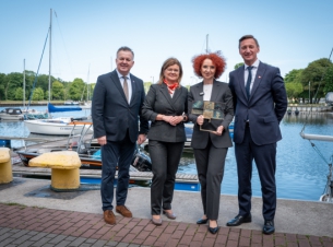 4 osoby, w tym prezydent Świnoujścia oraz marszałek, stoja w porcie, prezydentka trzyma statuetkę