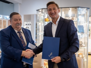 Marszałek Geblewicz i bumistrz Wyganowski gratulują sobie podpisania umowy, wtle szkolne gabloty z upominkami.